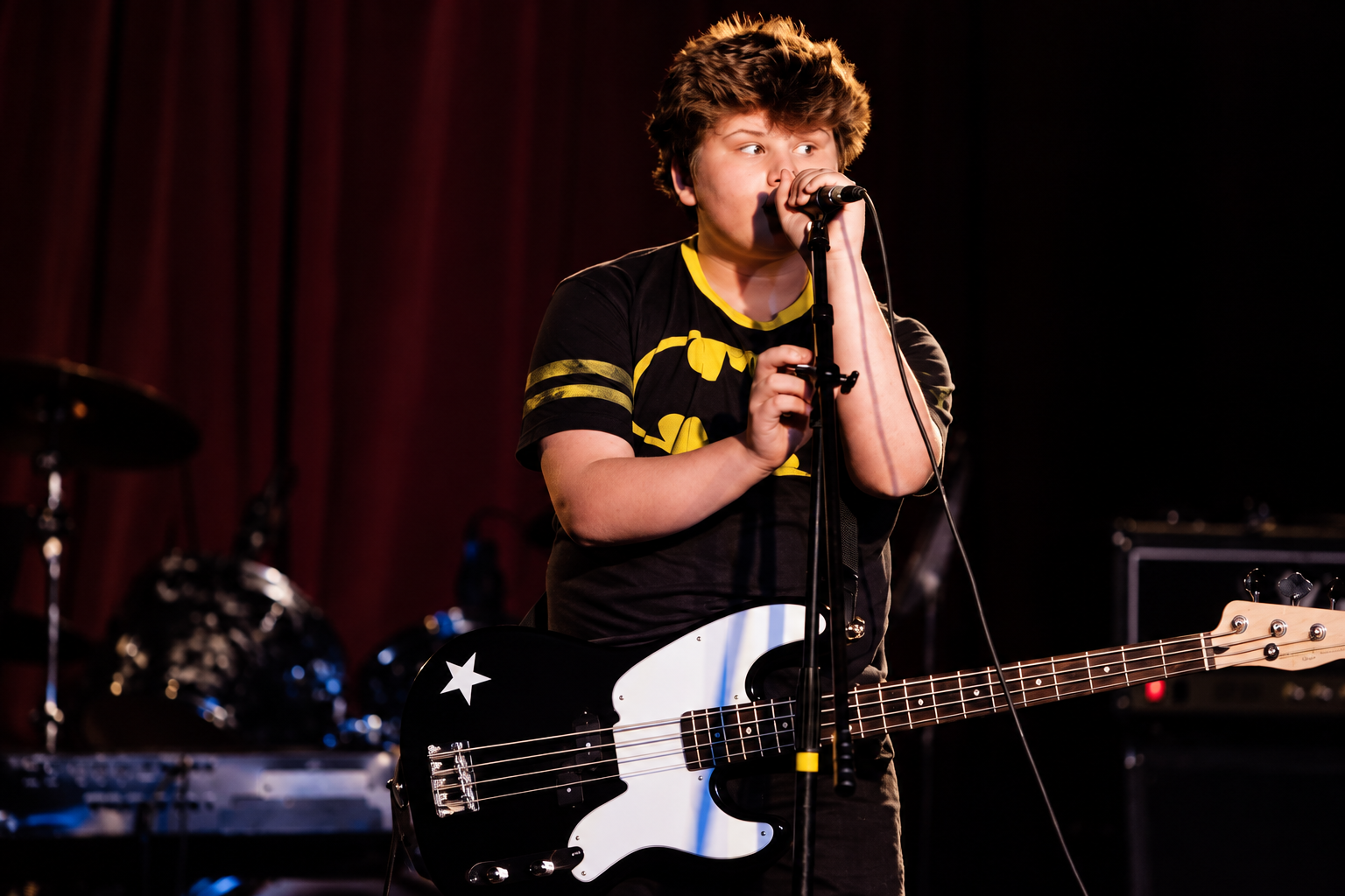 Teen musician playing bass and voice on an MBMS stage