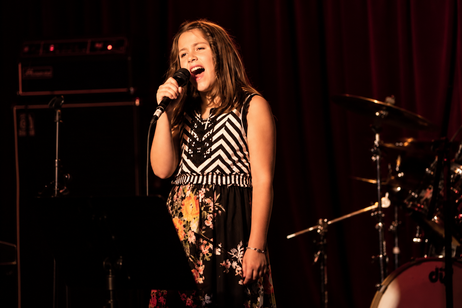 Teen singer holding a microphone on an MBMS stage