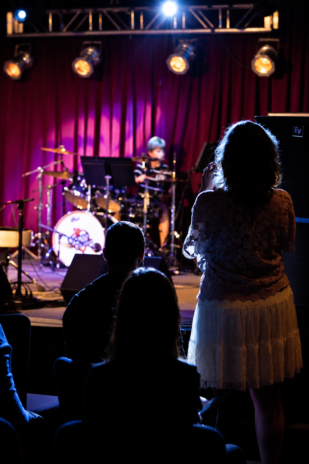Vocalist and drum kit under stage lights · MBMS archive