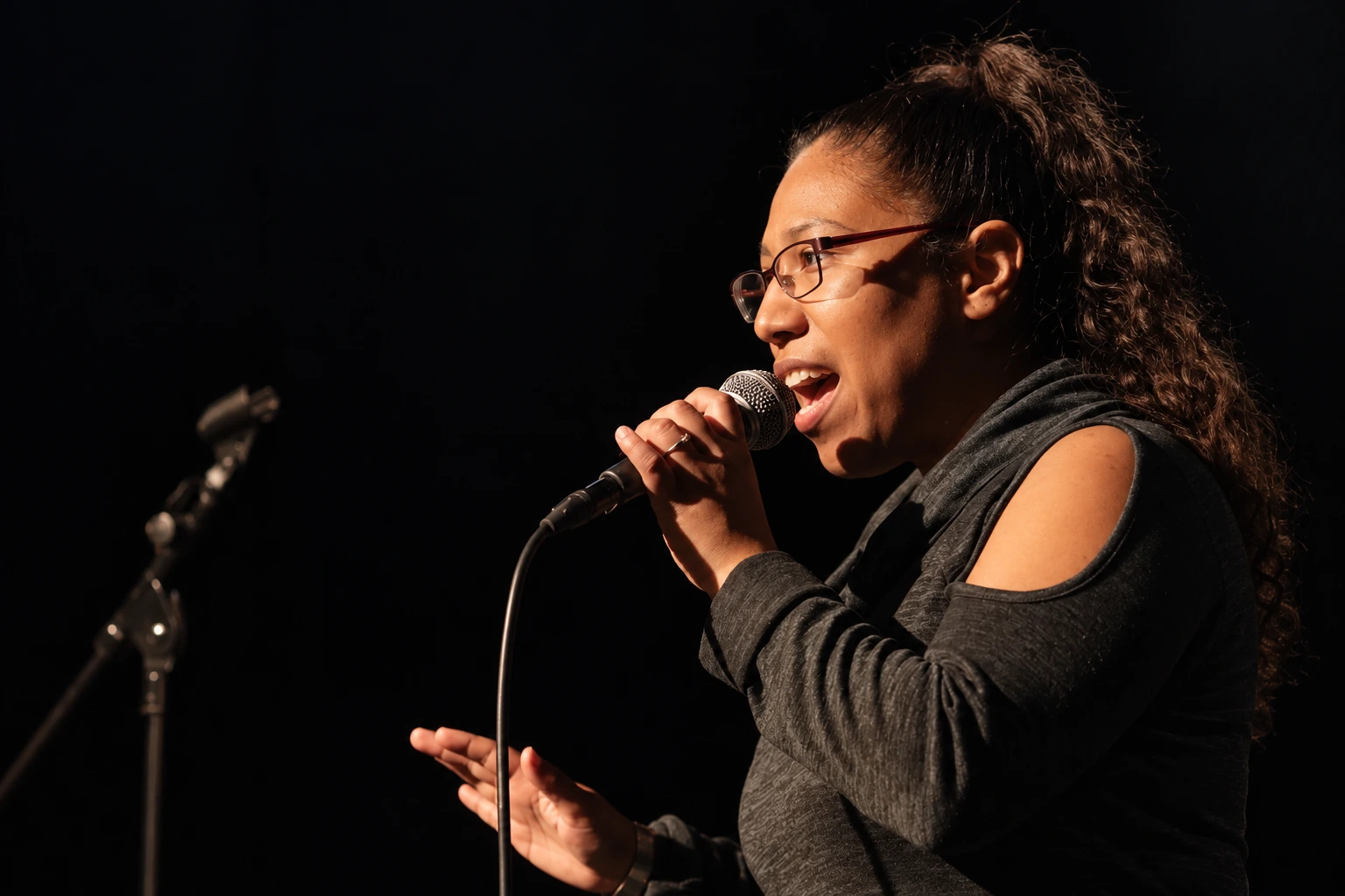 Vocalist wearing glasses singing into a handheld microphone