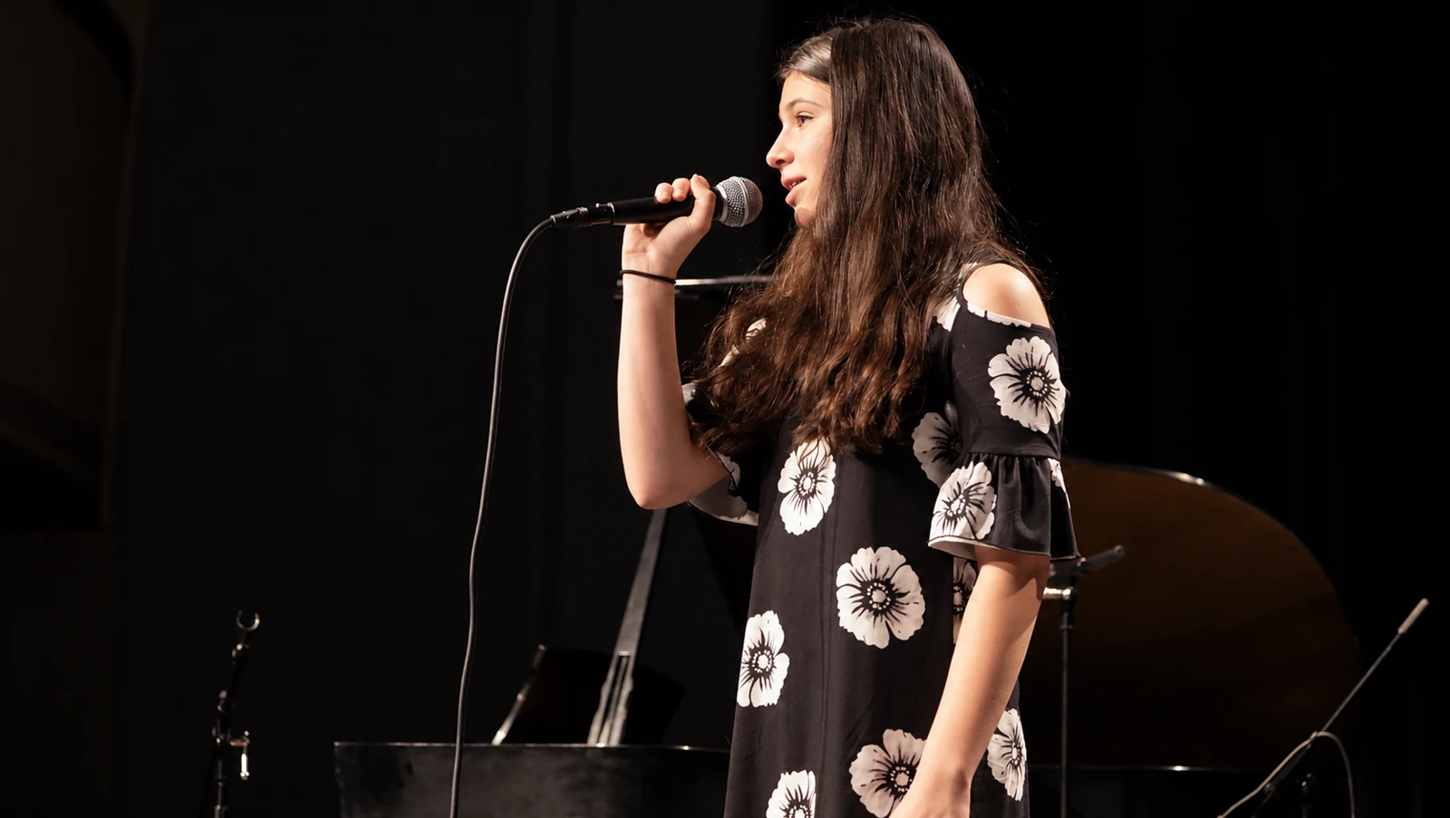MBMS singer holding a microphone on an MBMS stage