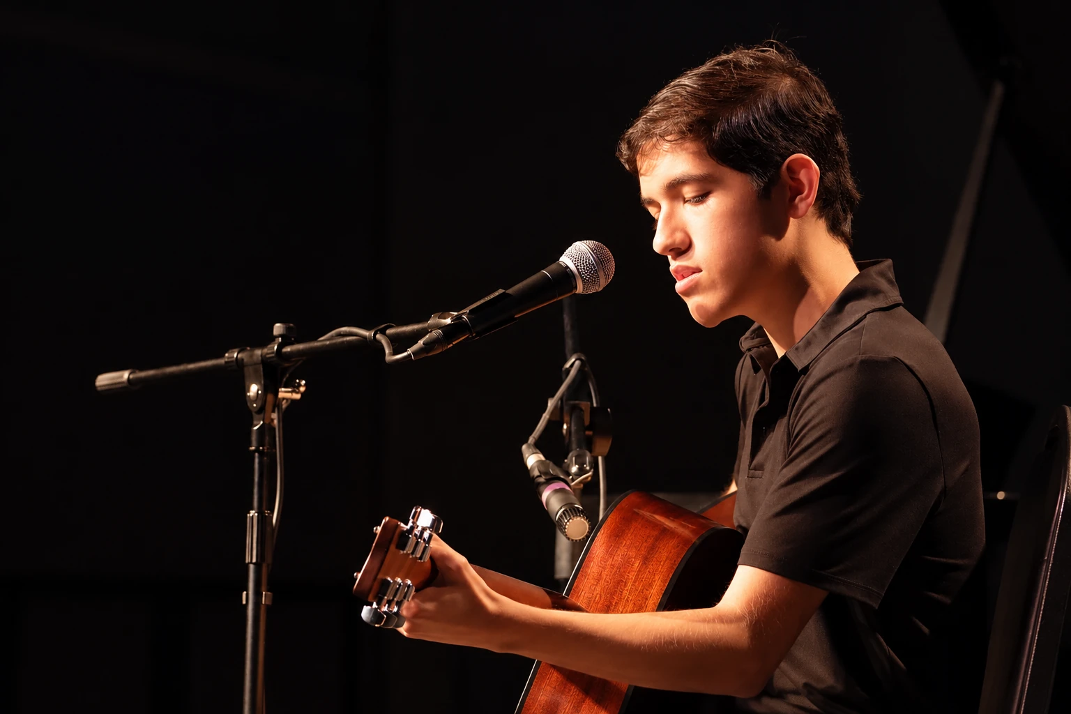 Teen musician playing acoustic guitar and voice on an MBMS stage