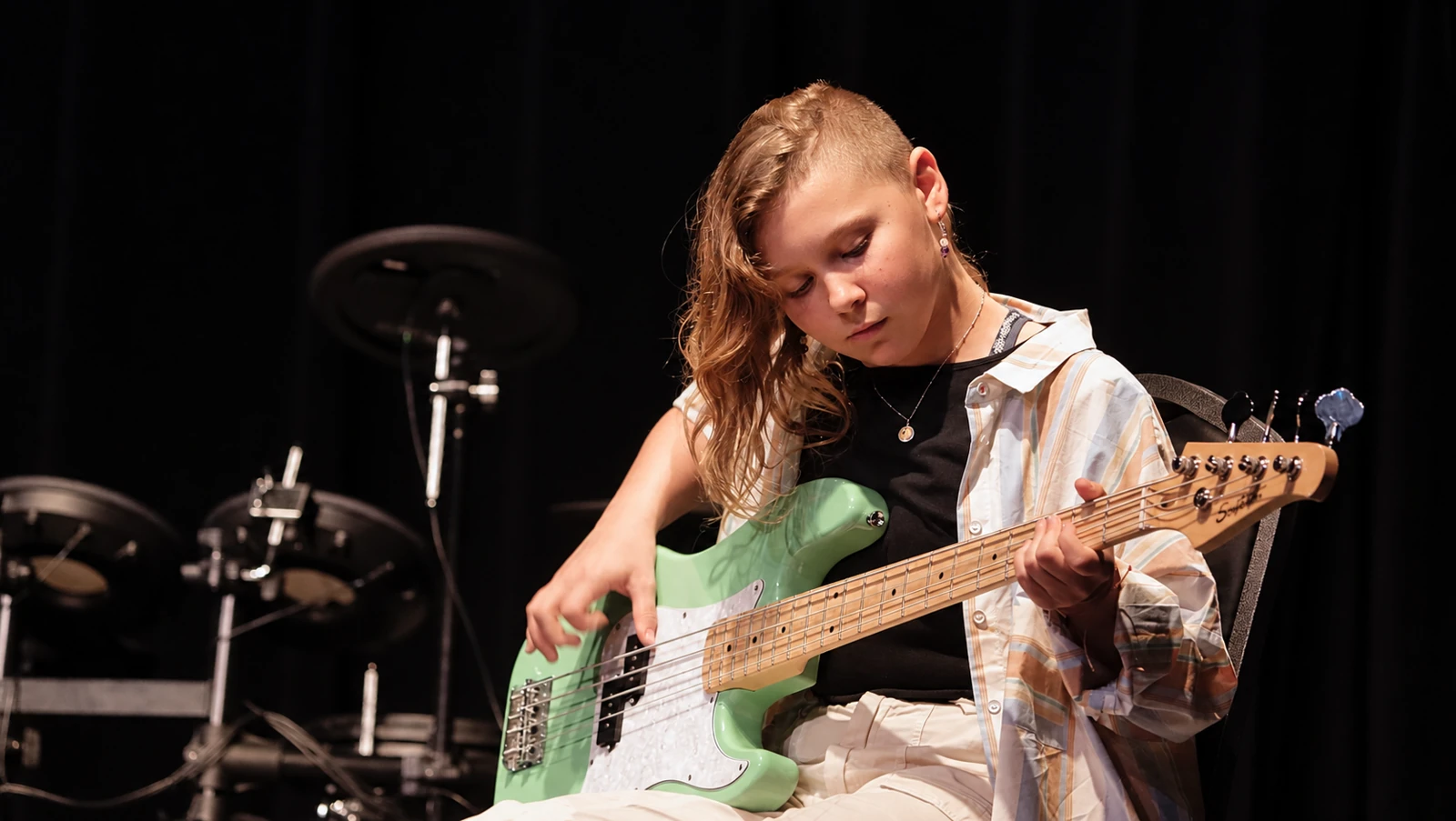 Teen musician playing bass on an MBMS stage