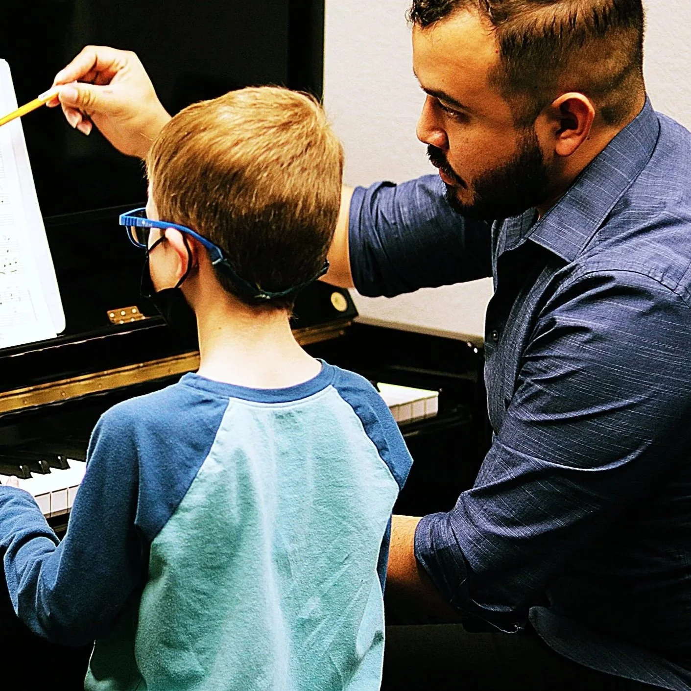 A teacher guiding a student at the piano